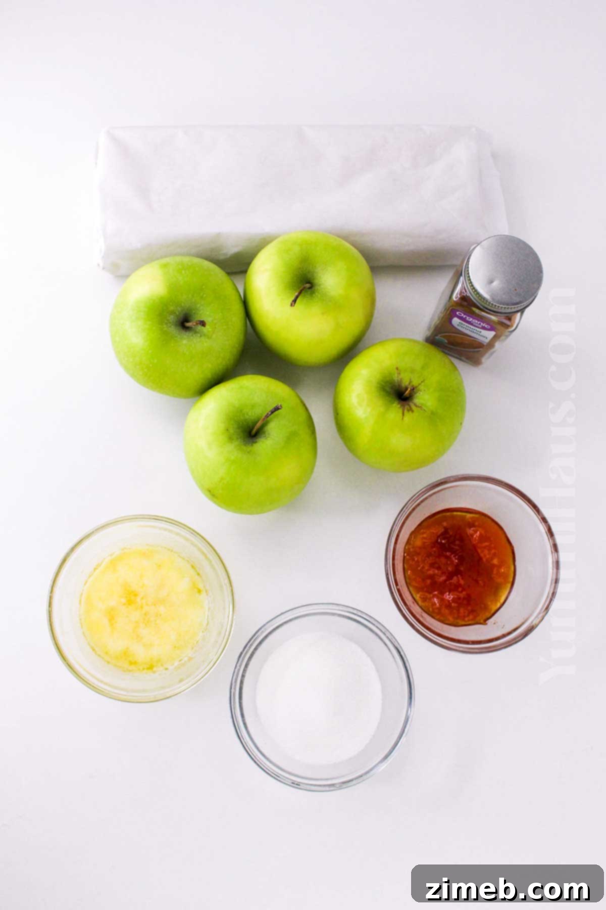 Close-up of fresh ingredients for Easy Puff Pastry Apple Tart including a puff pastry sheet, sliced apples, butter, sugar, and cinnamon.