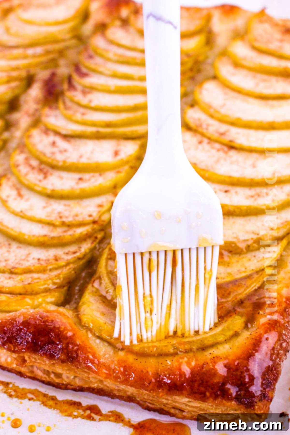 Applying a shimmering apricot glaze to a freshly baked Puff Pastry Apple Tart, creating a beautiful, glossy finish.