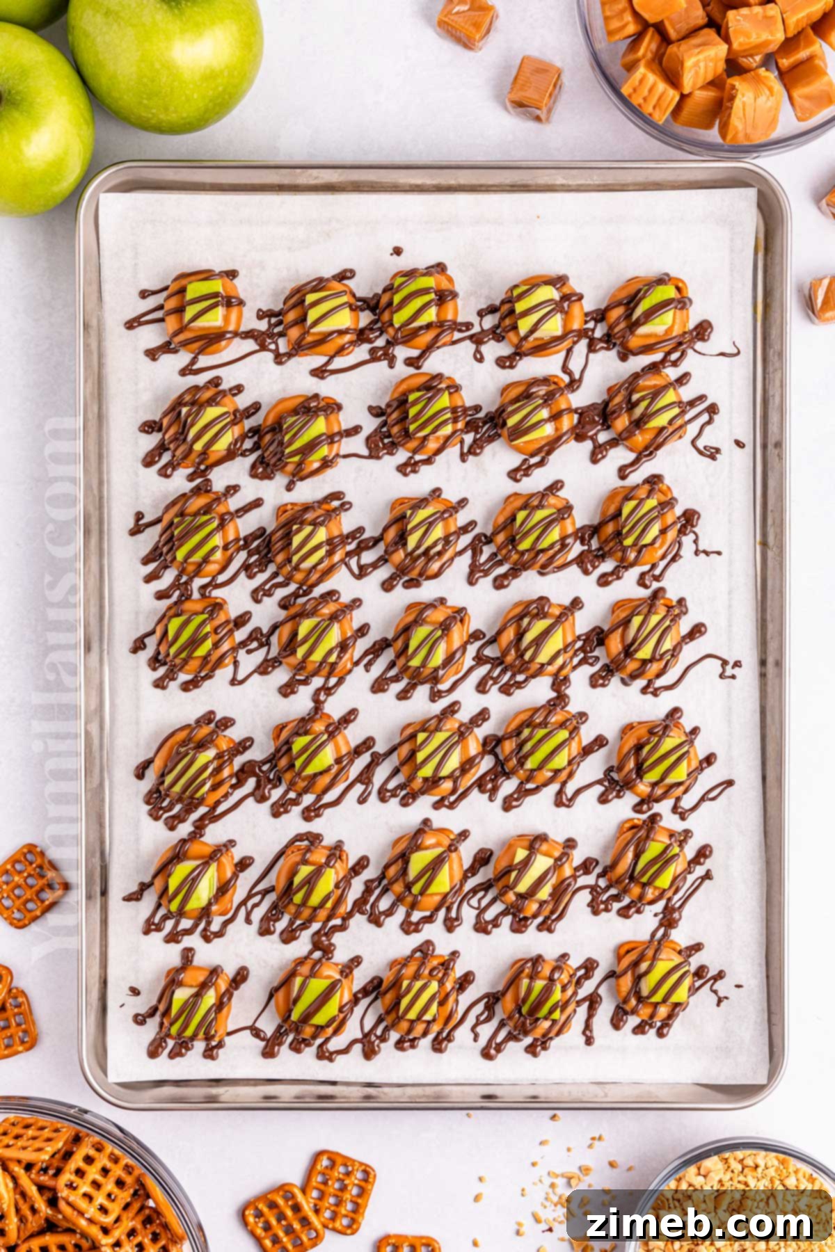 Sweet and Salty Caramel Apple Pretzel Bites 6 A hand adding a chocolate drizzle to the caramel apple pretzel bites.