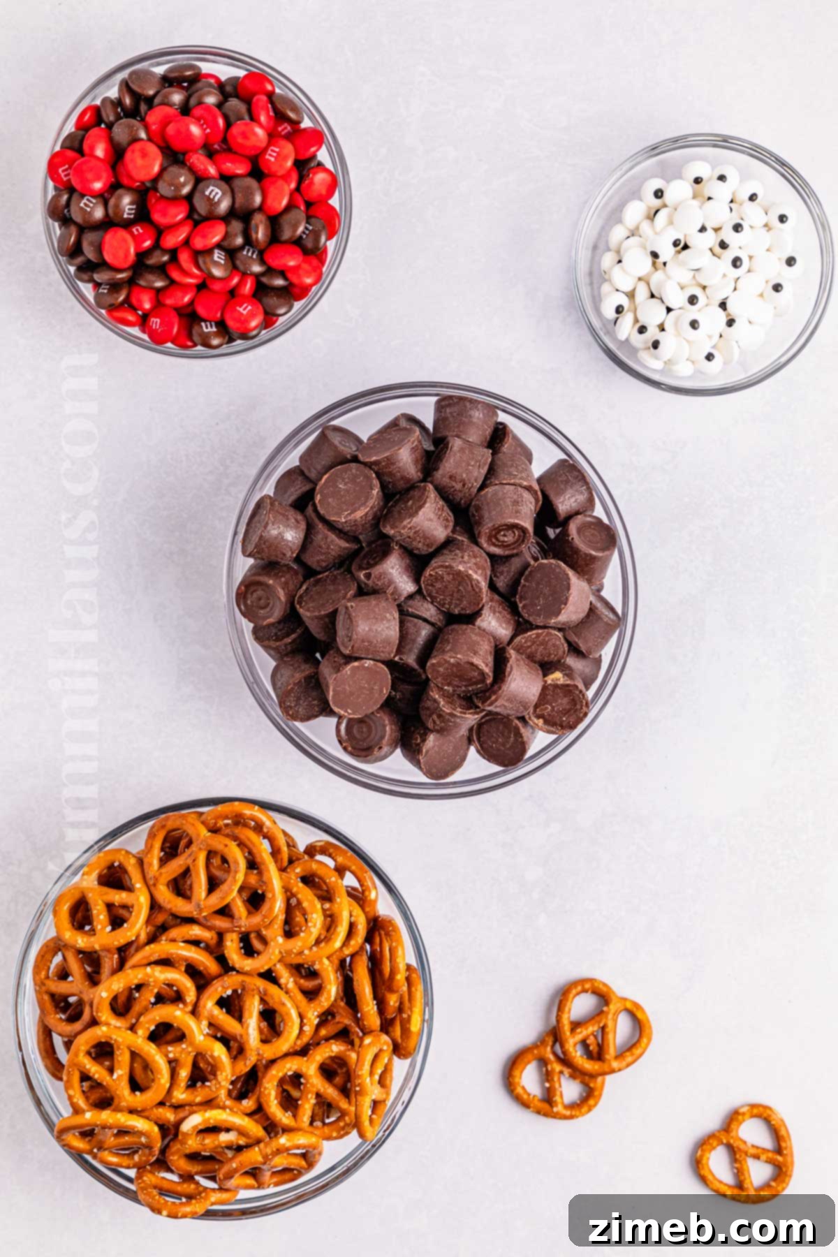 Ingredients laid out for Reindeer Rolo Pretzels, showcasing pretzels, Rolos, M&Ms, and candy eyeballs.