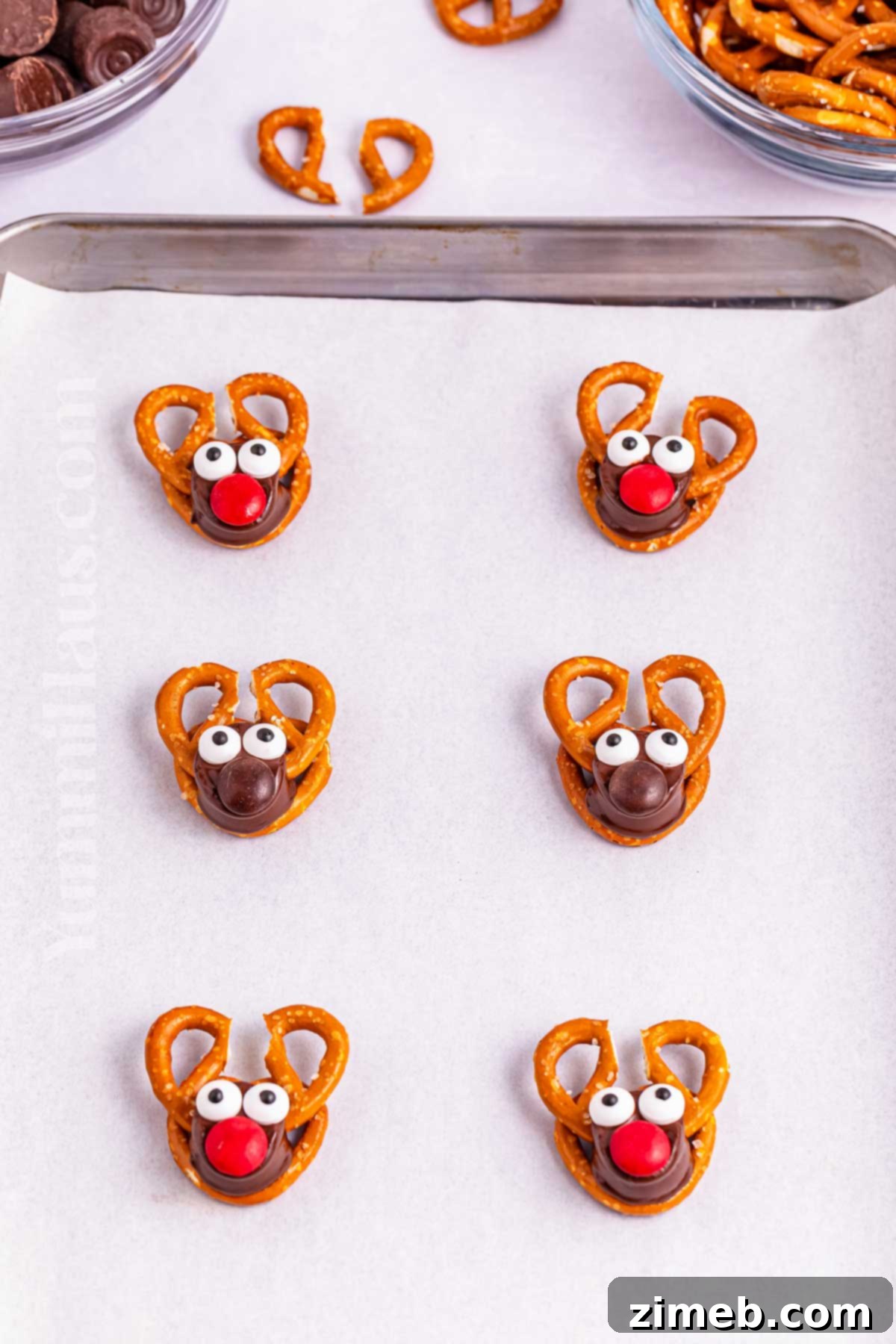 Assembling Reindeer Rolo Pretzels with antlers, candy eyeballs, and M&M noses.