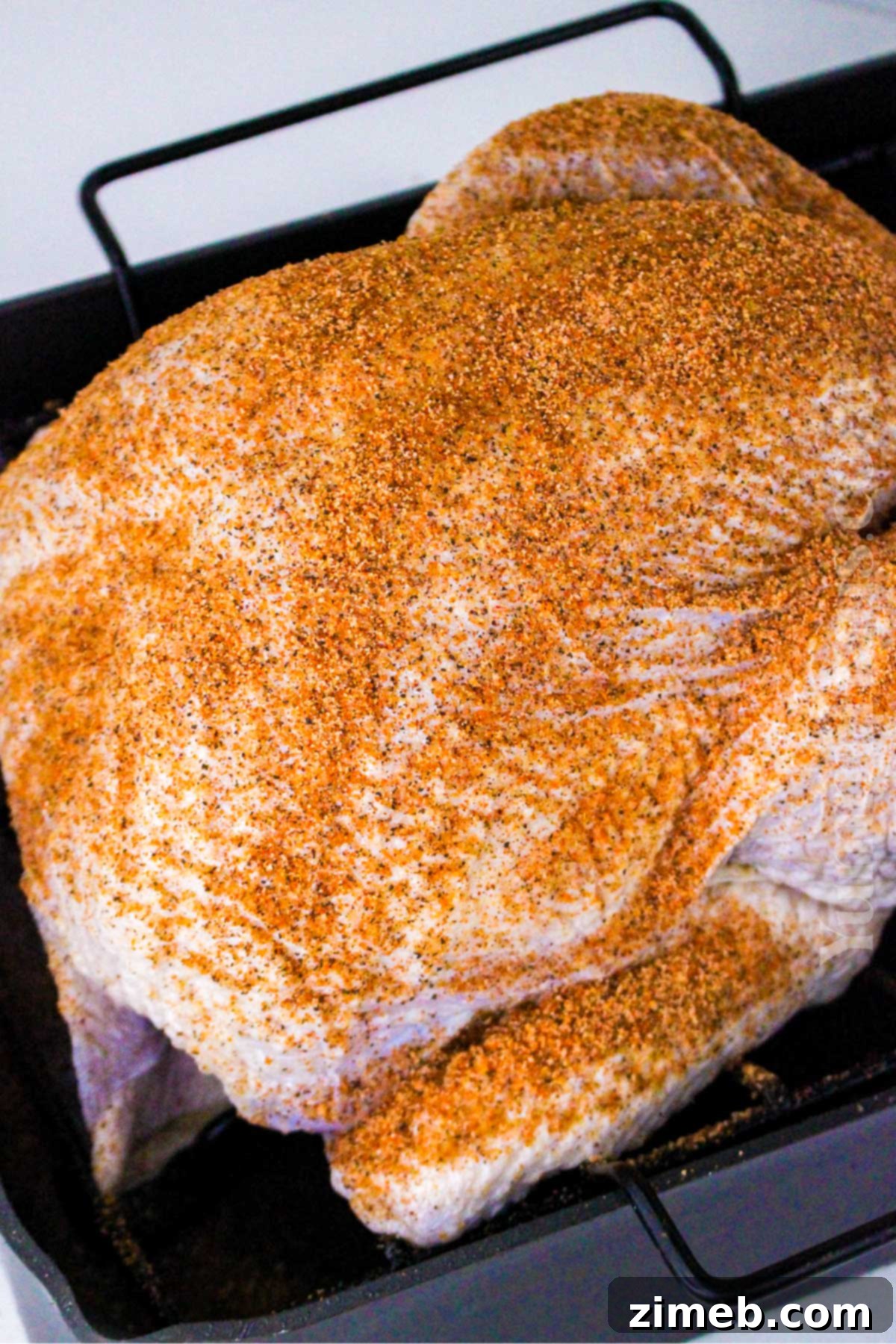 Seasoning a brined turkey with Cajun rub before cooking