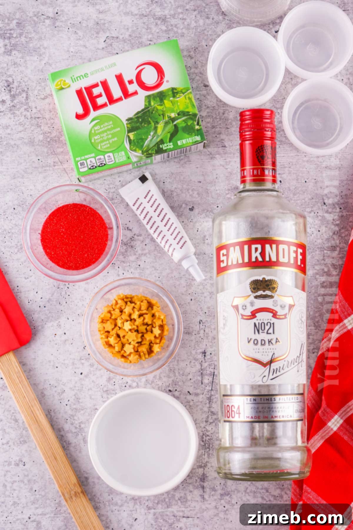 Ingredients for making Christmas Jello Shots, including lime jello, vodka, and festive sprinkles.