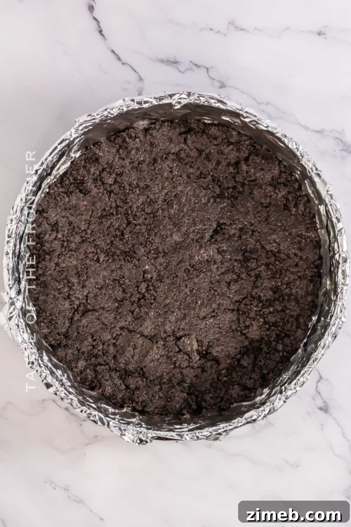 Decadent Oreo Mousse Cake 5 Close-up of preparing Oreo crust with crushed Oreos and melted butter.