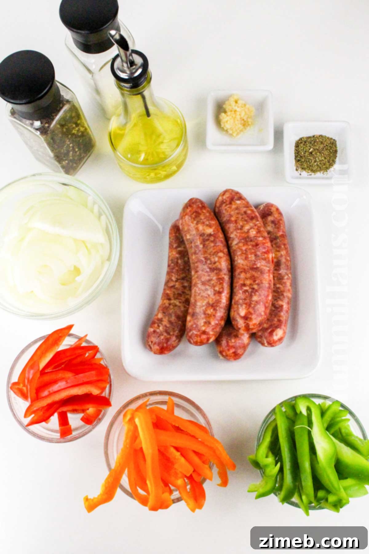 Fresh ingredients for Baked Italian Sausage including bell peppers, onions, and sausage links.