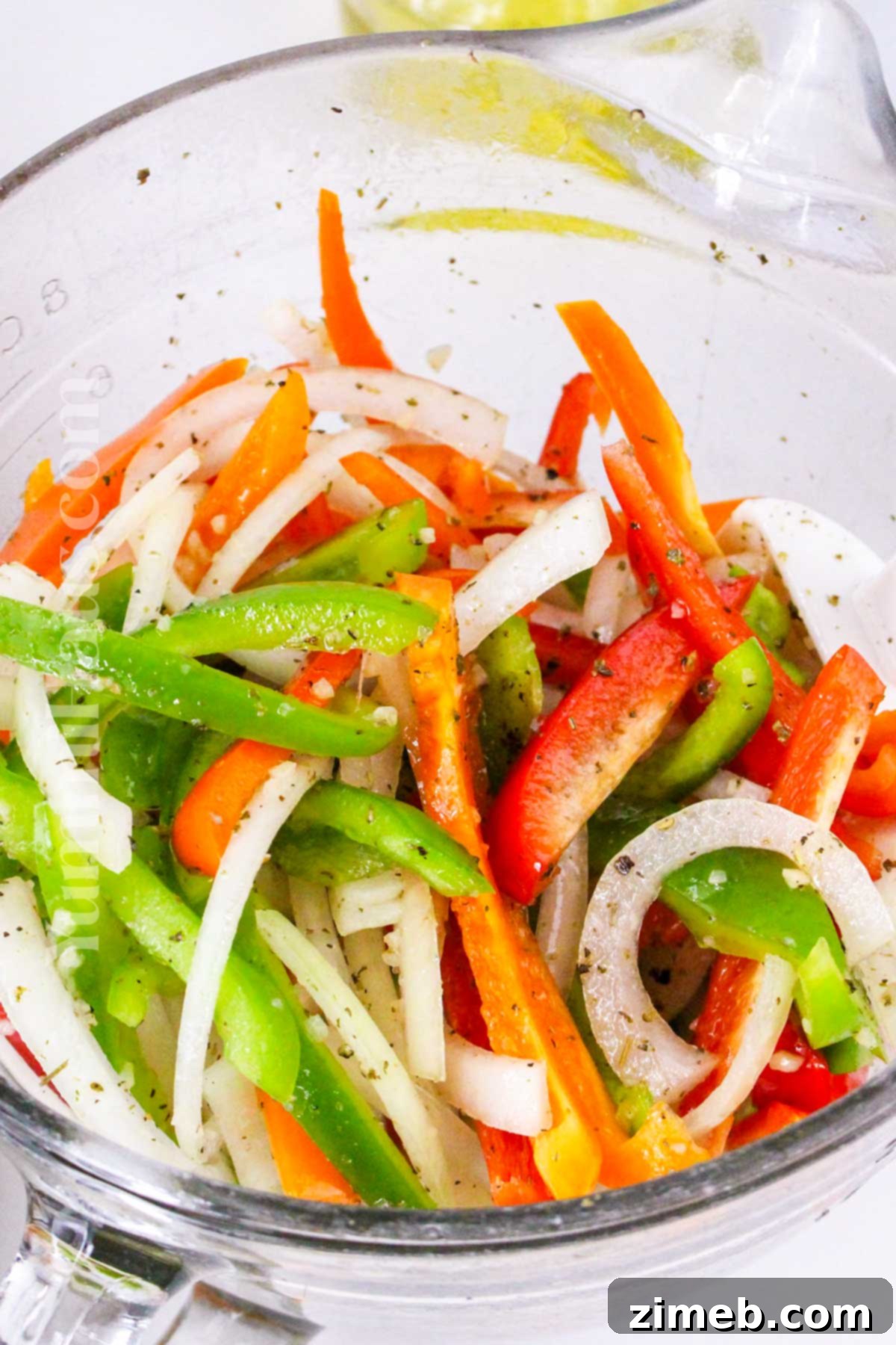 Seasoning bell peppers and onions before baking with Italian sausage.