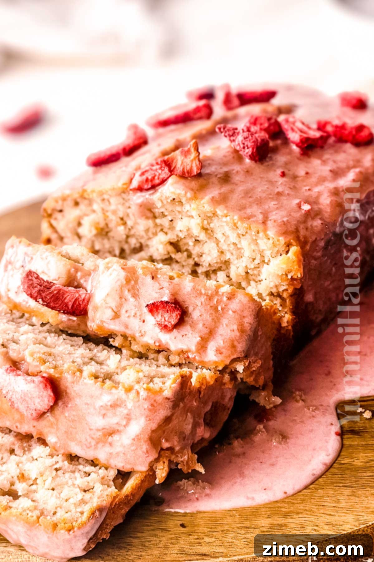 Close-up of a slice of strawberry cake with pink frosting and fresh berries.