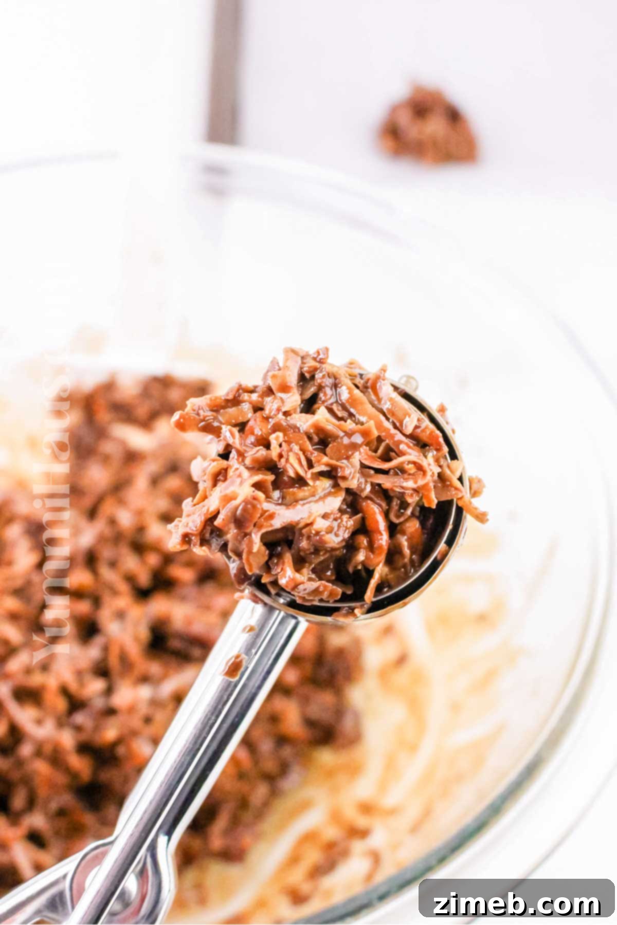 Scooping coated coconut mixture onto a baking sheet for keto clusters