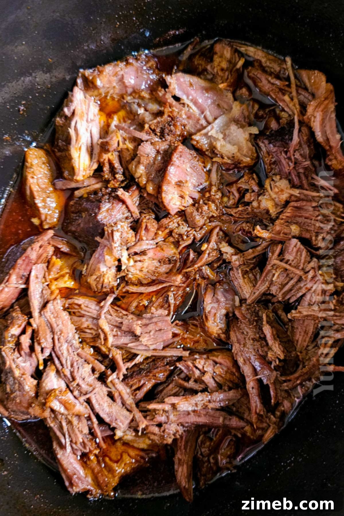 Melt-in-Your-Mouth Shredded Beef 7 Pulled beef simmering in the Crockpot