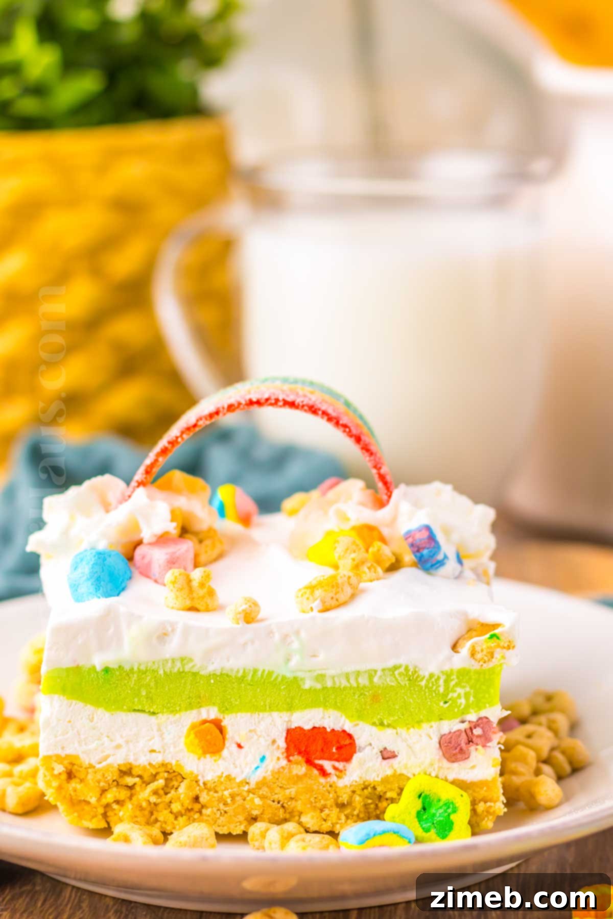 Rainbow Charm Elixir 16 A slice of Lucky Charms Lush, showcasing the distinct creamy, green, and pudding layers with a crunchy crust and marshmallow topping