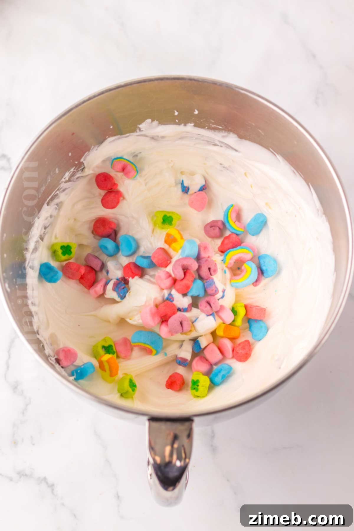 Rainbow Charm Elixir 6 Close-up of Lucky Charms marshmallows being mixed into the pudding layer of the lush dessert