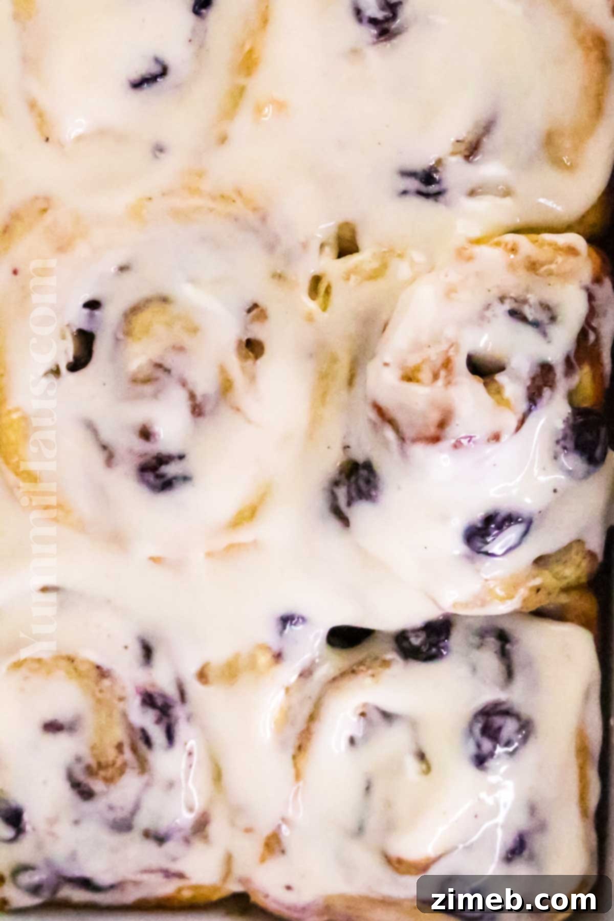 Luscious Blueberry Cinnamon Swirls 15 Delicious and vibrant blueberry cinnamon rolls on a rustic wooden table, ready to be enjoyed.