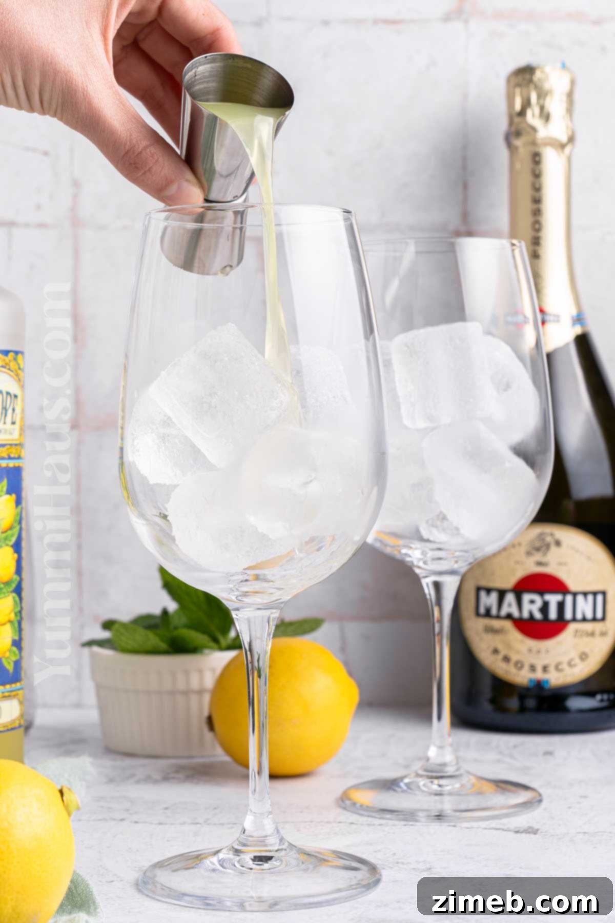 Refreshing Limoncello Spritz 5 Hands pouring limoncello into a glass filled with ice, preparing a Limoncello Spritz
