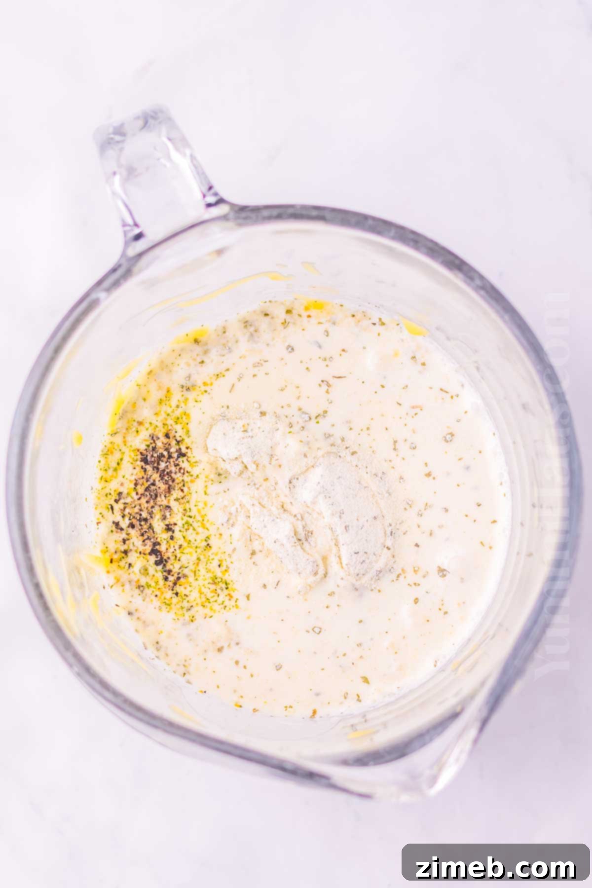 Pouring creamy ranch sauce over pork chops in a slow cooker, illustrating how to make the dish.