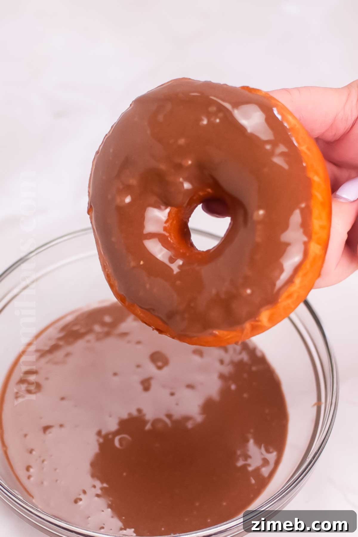 adding the chocolate glaze to sourdough donuts