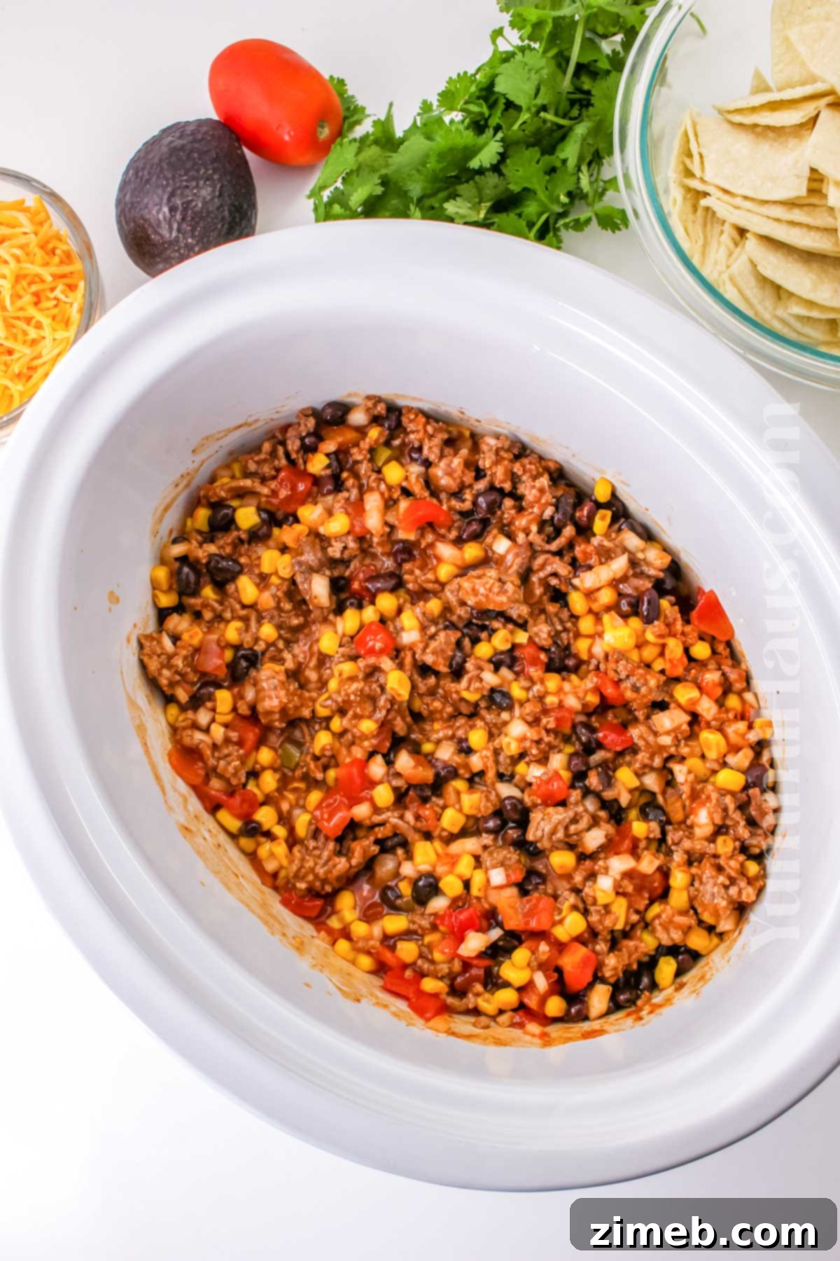 Easy Slow Cooker Mexican Casserole 6 Portion of Crockpot Mexican Casserole served on a plate with fresh avocado and cilantro.