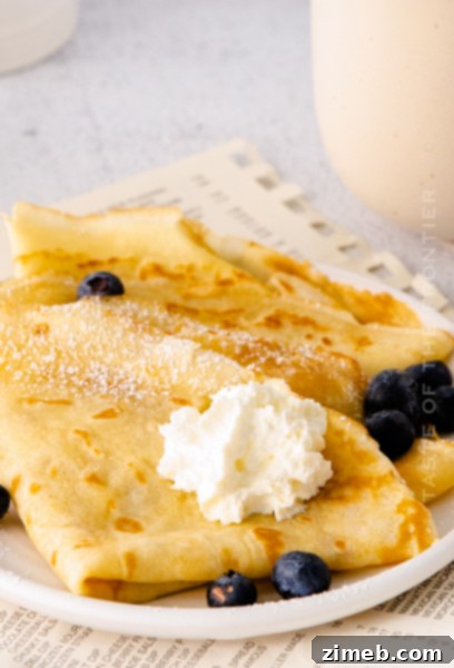 Delicate, golden crepes stacked on a plate, ready to be filled with sweet or savory toppings.