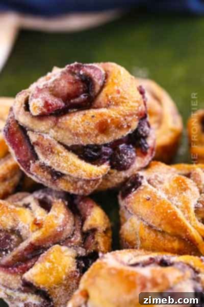 Golden brown Blueberry Cruffins, showcasing the flaky layers of croissant dough filled with juicy blueberry pie filling, baked in muffin tins.
