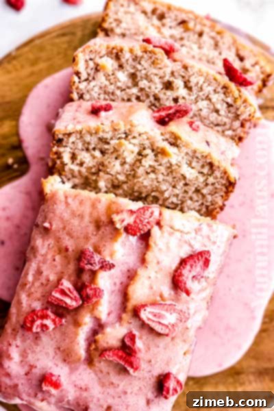 Moist Strawberry Loaf Cake with pink glaze and fresh berries for Mother's Day.