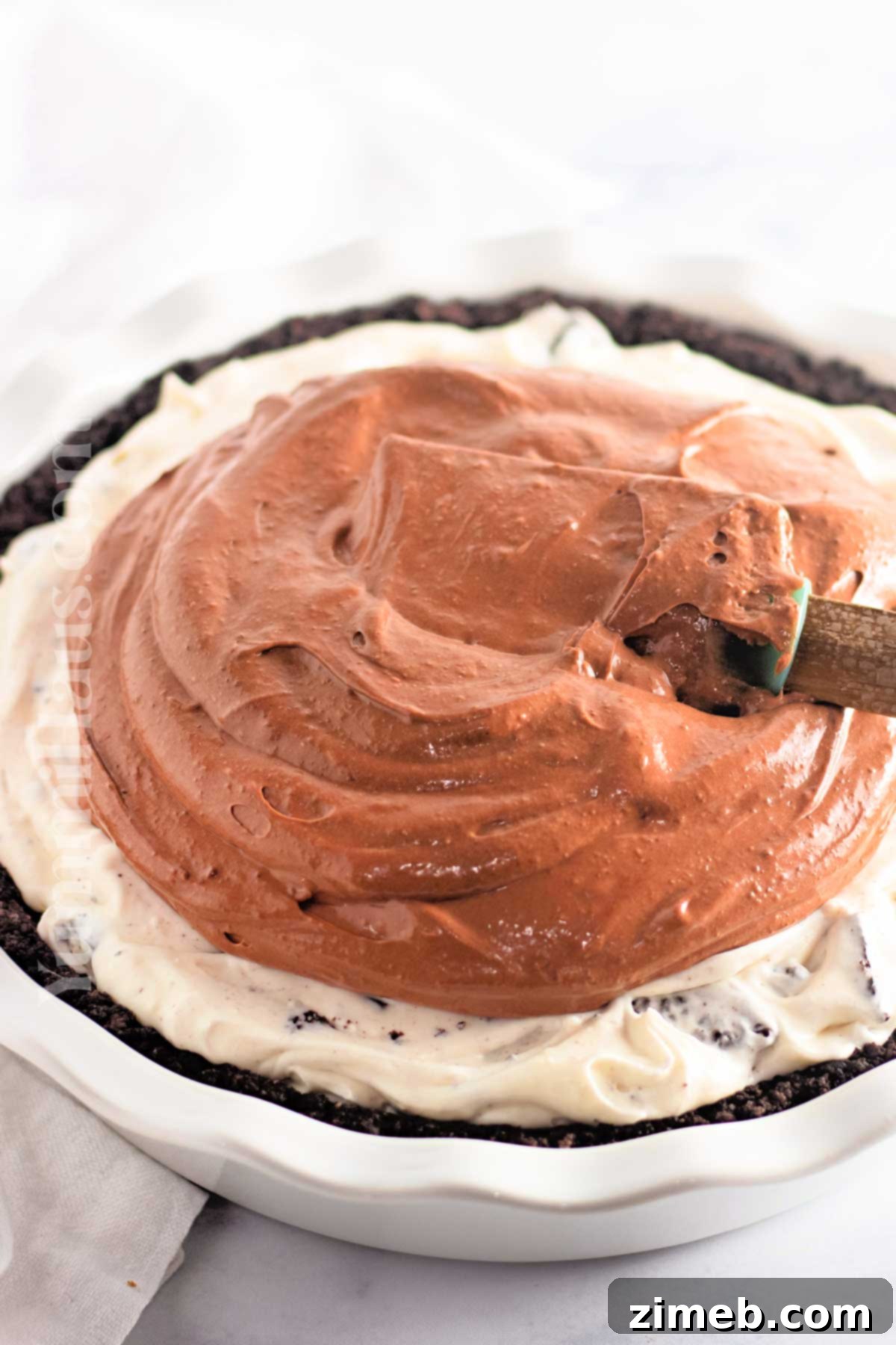 Close-up of the two cream layers being spread into the Oreo pie crust