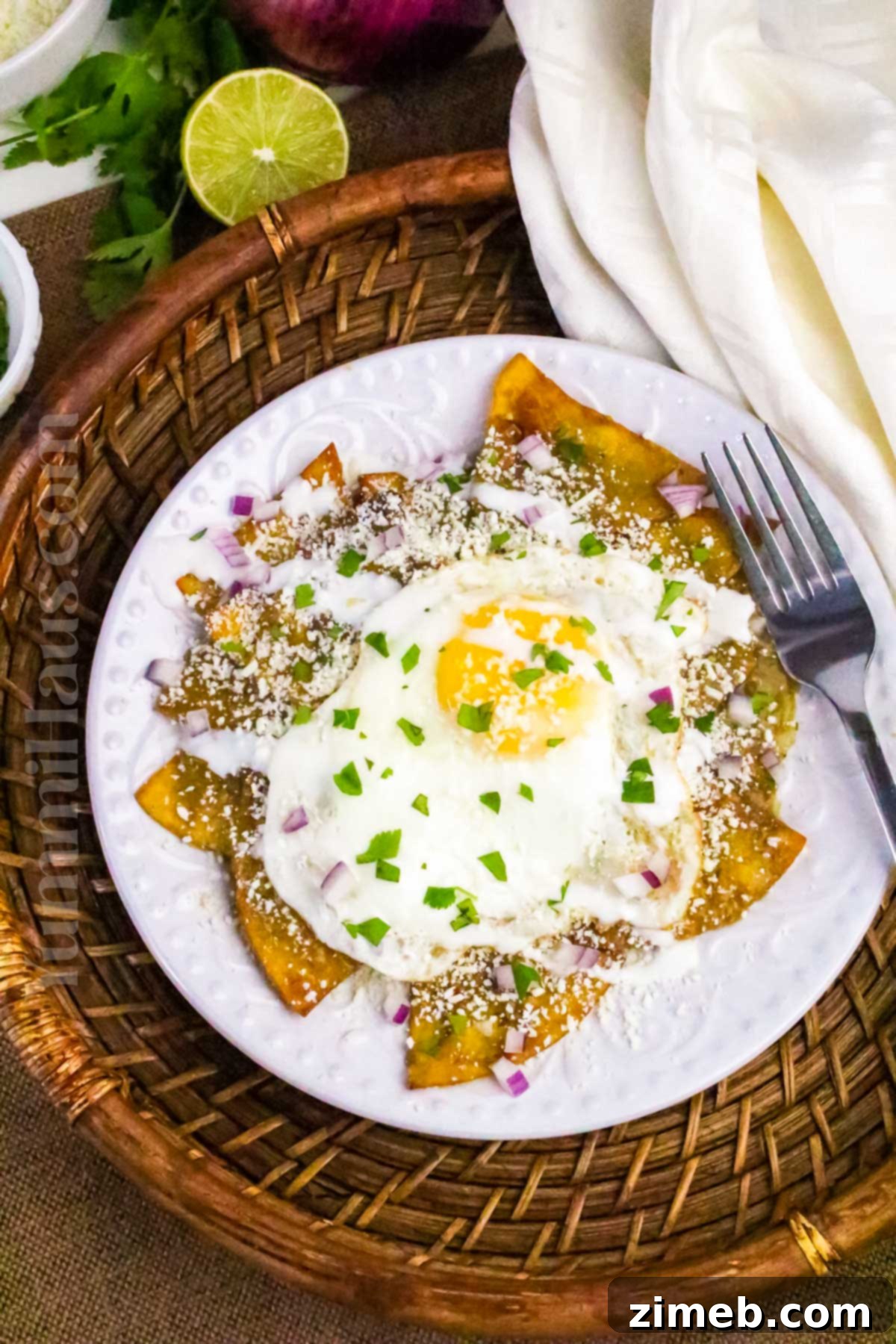 Authentic Chilaquiles Verdes: Crispy tortilla chips simmered in tangy green salsa, topped with crema, cheese, and your choice of eggs or chicken for a classic Mexican breakfast.