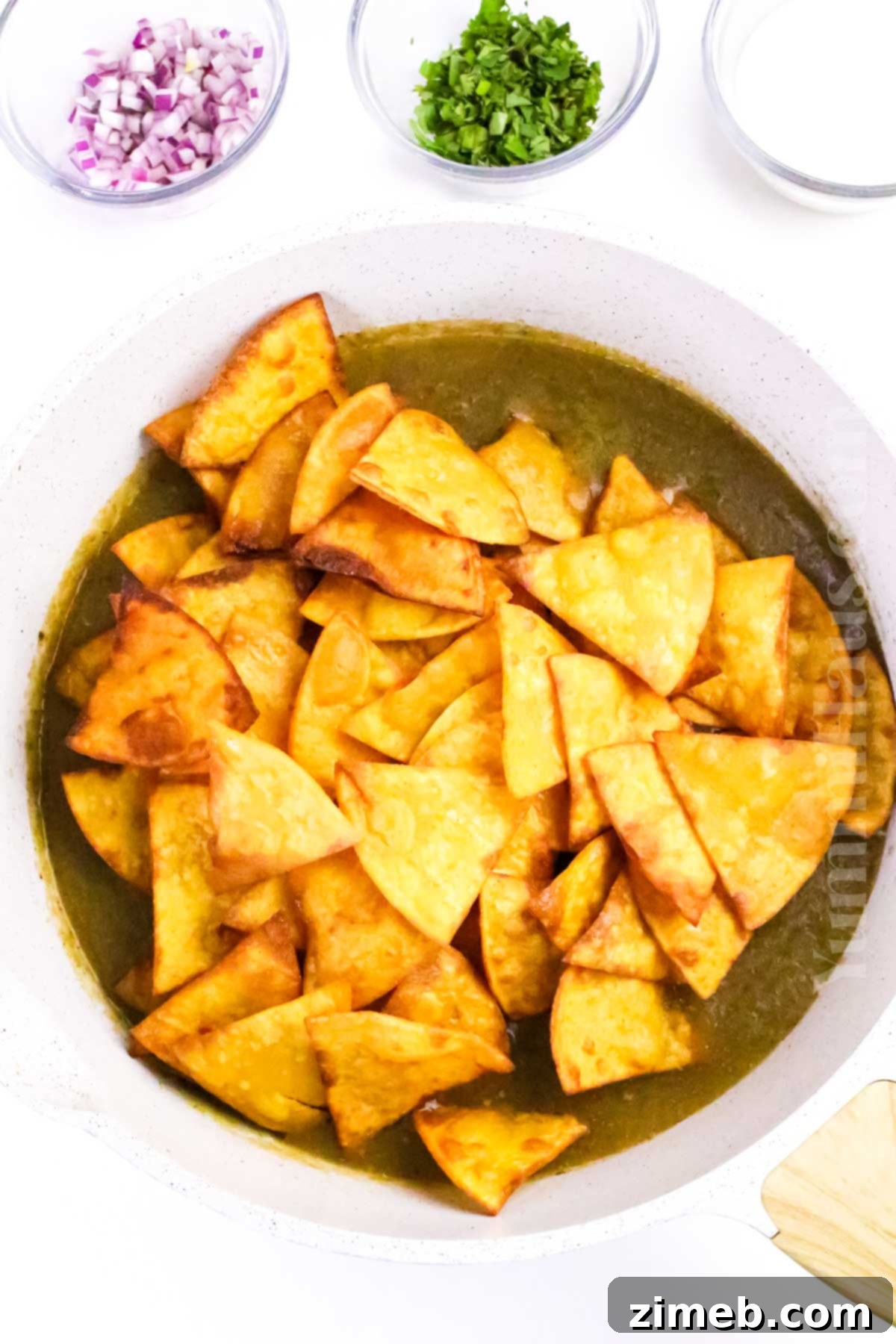 Step-by-step guide to making Chilaquiles Verdes: adding crispy chips to simmering green salsa.