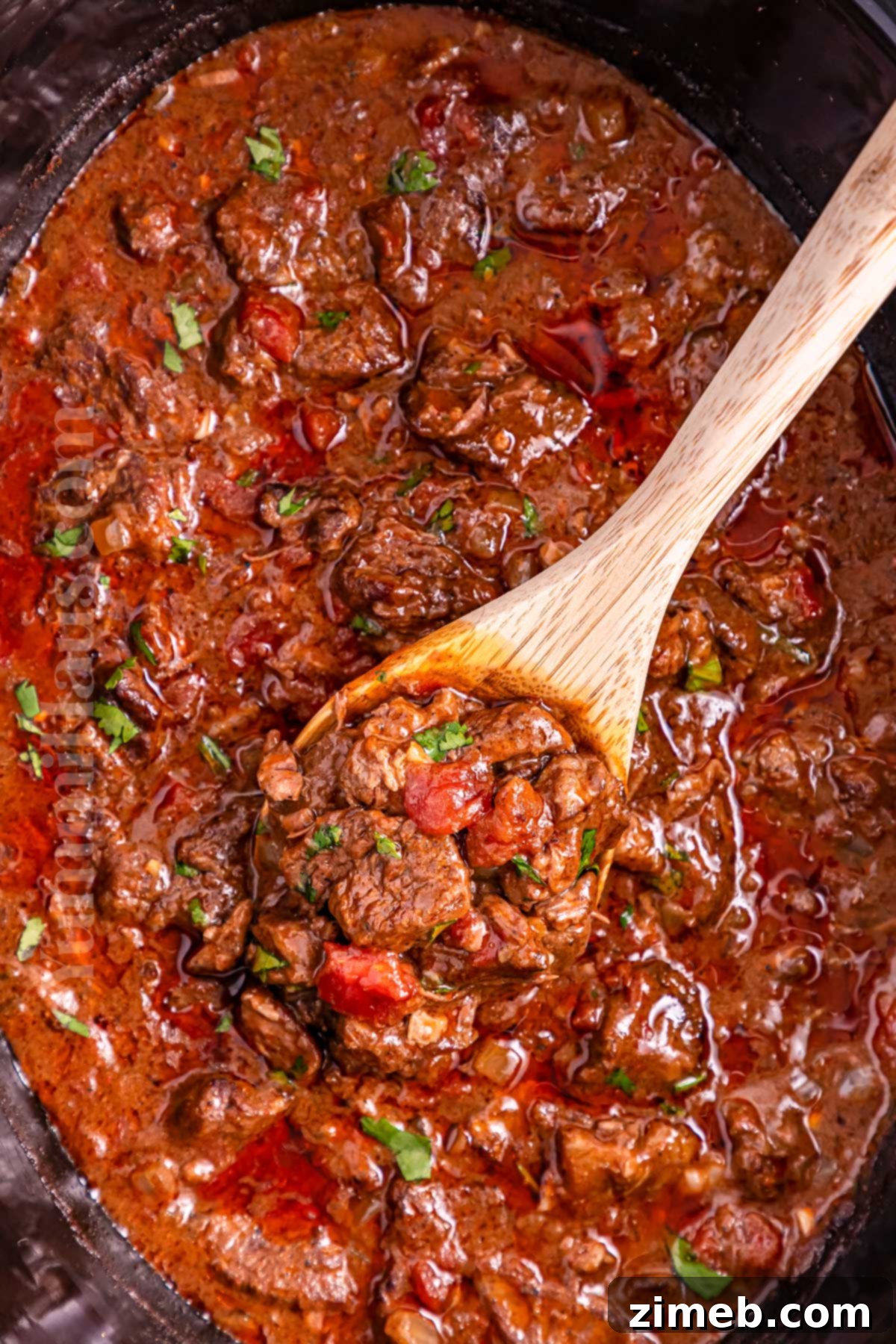 Fall-Apart Tender Slow Cooker Beef Curry 13 A bowl of rich Indian curry in a slow cooker, simmering.