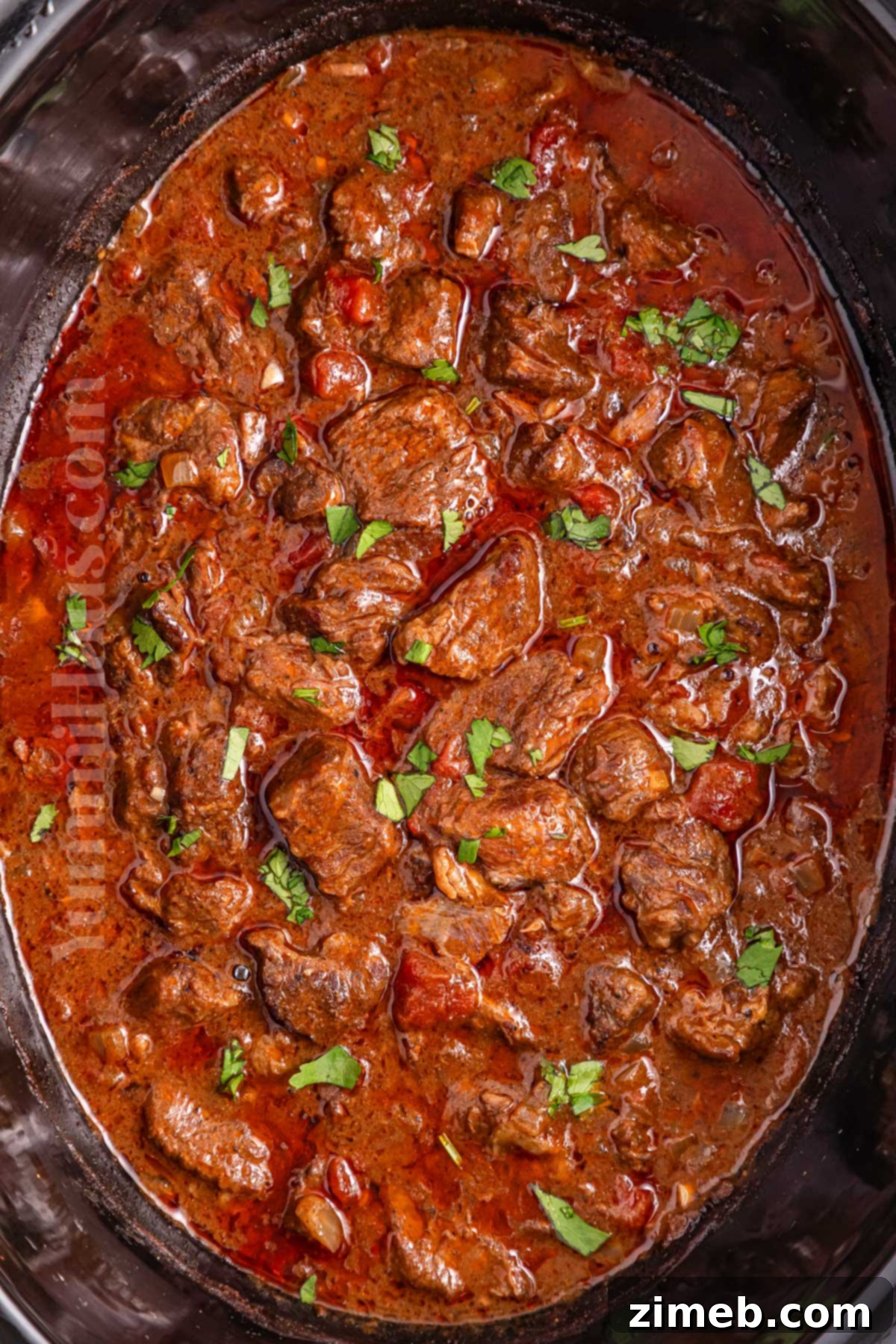 Fall-Apart Tender Slow Cooker Beef Curry 6 A serving of Crockpot Curry Beef with rice and naan, garnished with fresh cilantro.