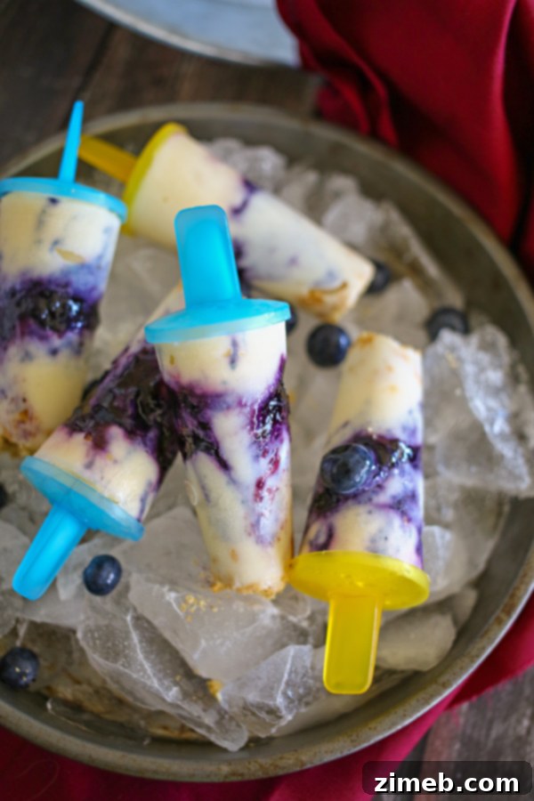 35 Refreshing Summer Frozen Treats 19 Blueberry Cheesecake Pops, a frozen version of cheesecake on a stick with blueberries and cream.