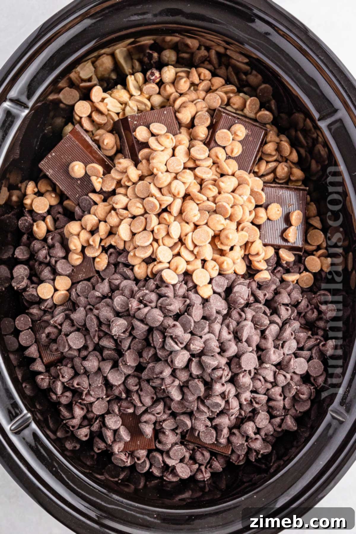 Scooping melted chocolate and nuts onto parchment paper for Crockpot Candy.