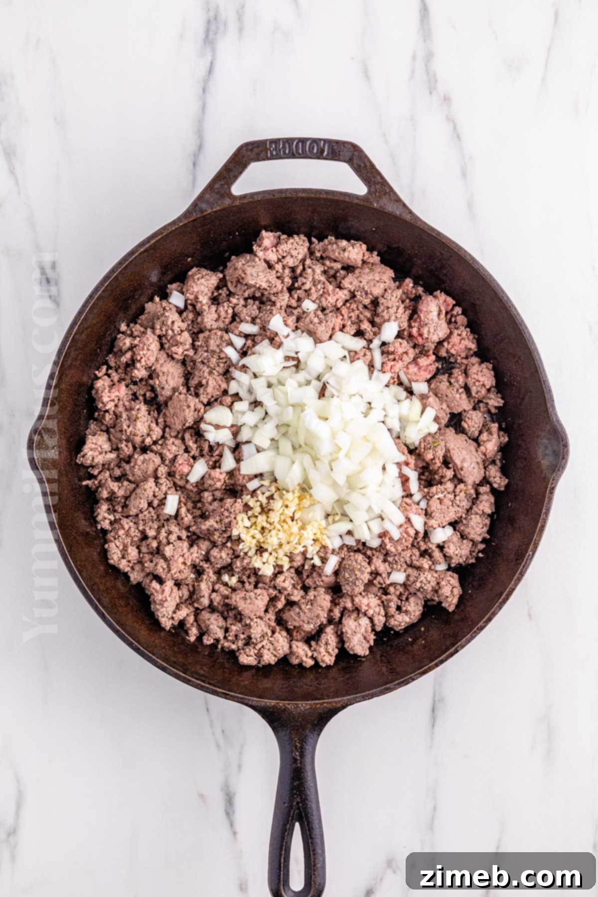 Ground beef, onions, and garlic browning in a skillet for lasagna soup