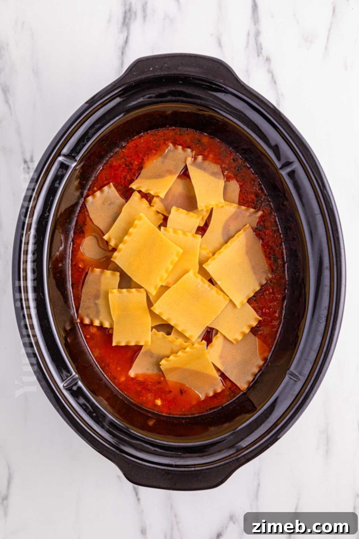 Adding broken lasagna noodles to the slow cooker for soup