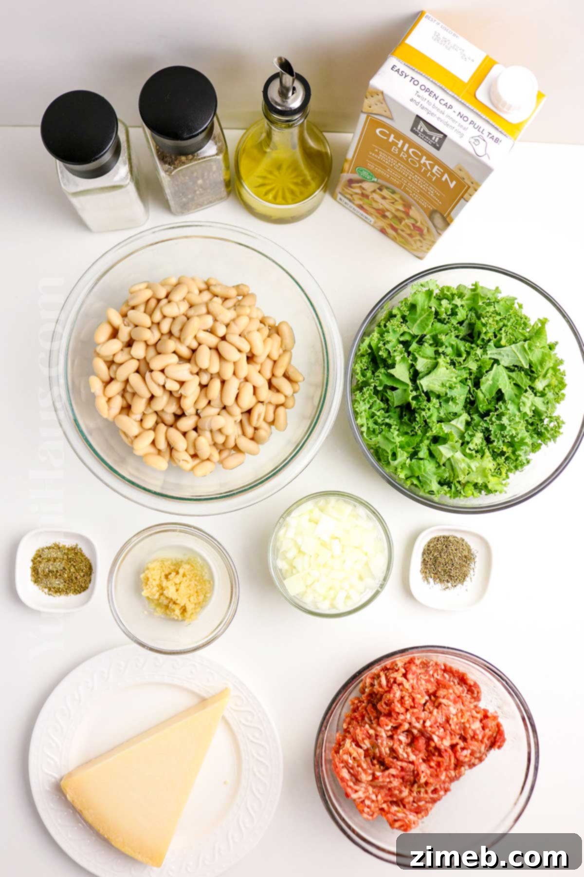 Tuscan Sausage, Kale, and White Bean Soup 4 Fresh ingredients laid out on a wooden board, including Italian sausage, cannellini beans, kale, onion, and garlic, ready for making soup.