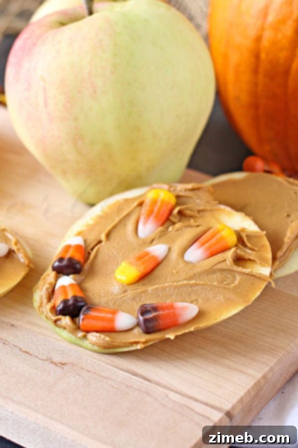 Kid-friendly Jack-o'-Lantern Candy Corn Apples, a healthy Halloween snack using apple slices, peanut butter, and candy corn.