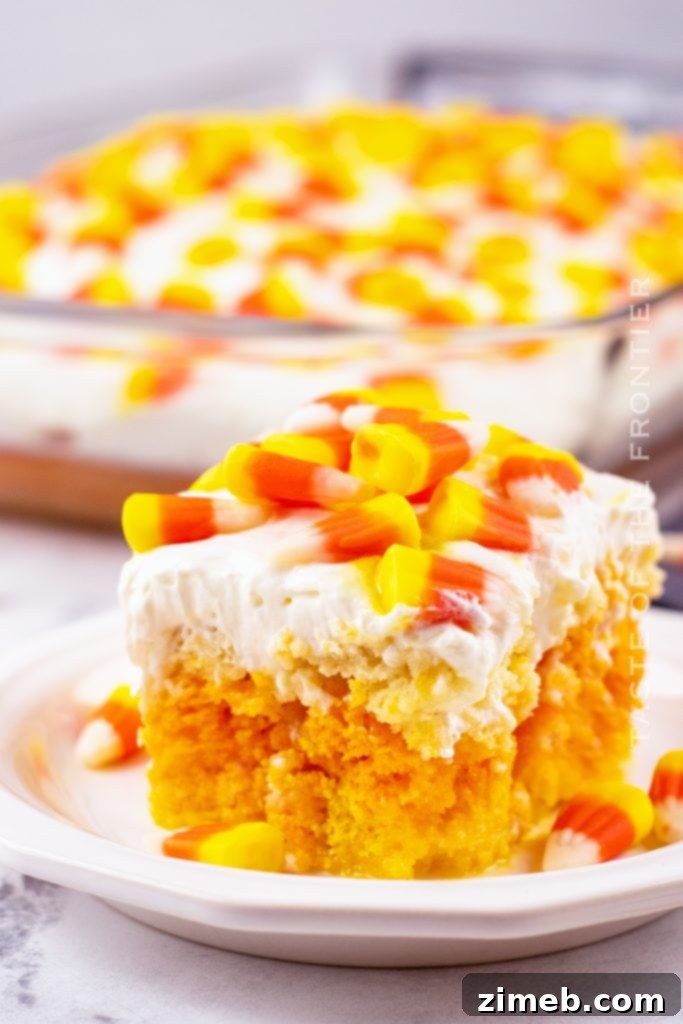 Festive Candy Corn Poke Cake topped with lush cream cheese frosting and decorated with candy corn, perfect for fall and Halloween parties.