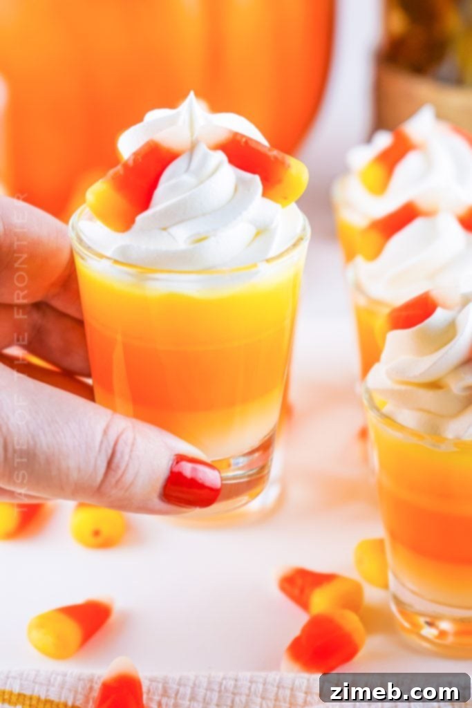 Fun and festive Candy Corn Jello Shots with layered orange, yellow, and white gelatin, whipped cream, and a touch of vodka for adult Halloween parties.