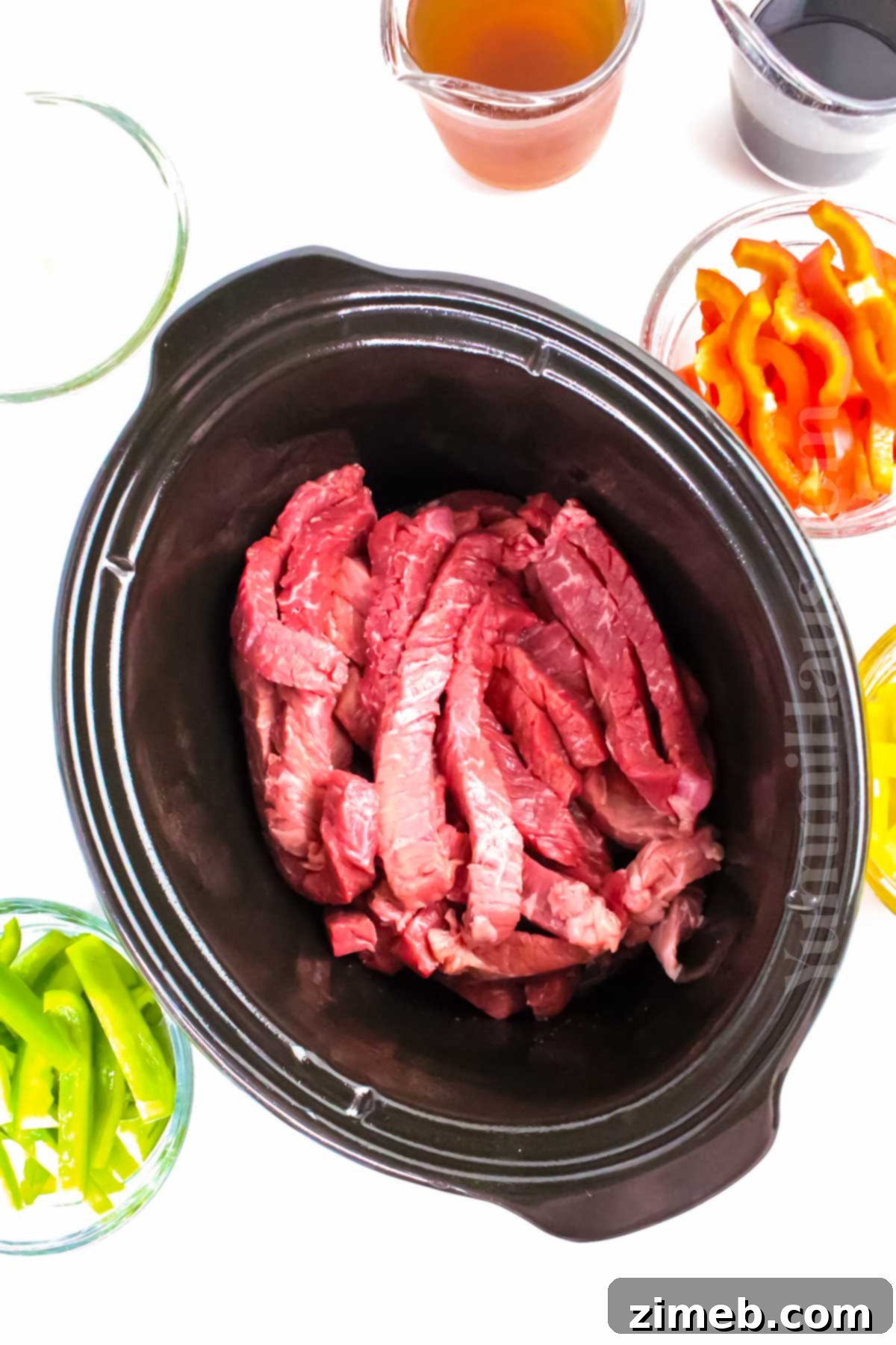 Tender Slow Cooker Pepper Steak 5 A bowl of Slow Cooker Pepper Steak served over rice, garnished with green onions.