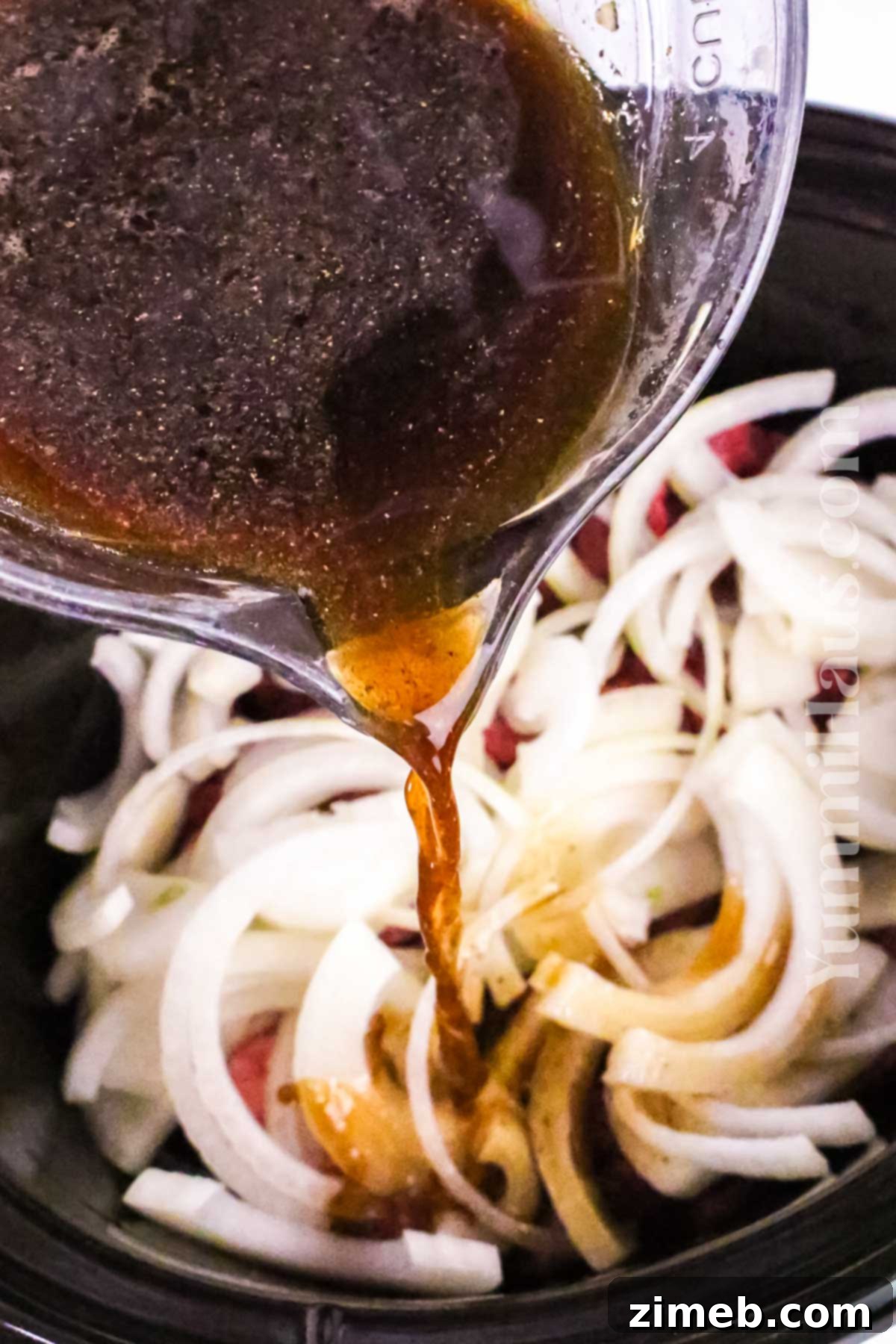 Tender Slow Cooker Pepper Steak 6 Hand pouring cornstarch slurry into the slow cooker to thicken the pepper steak sauce.