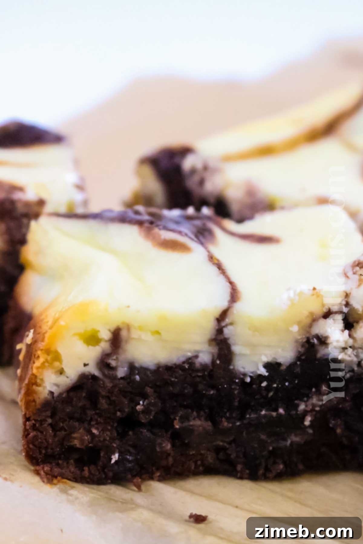 layers of brownie and cheesecake in a square