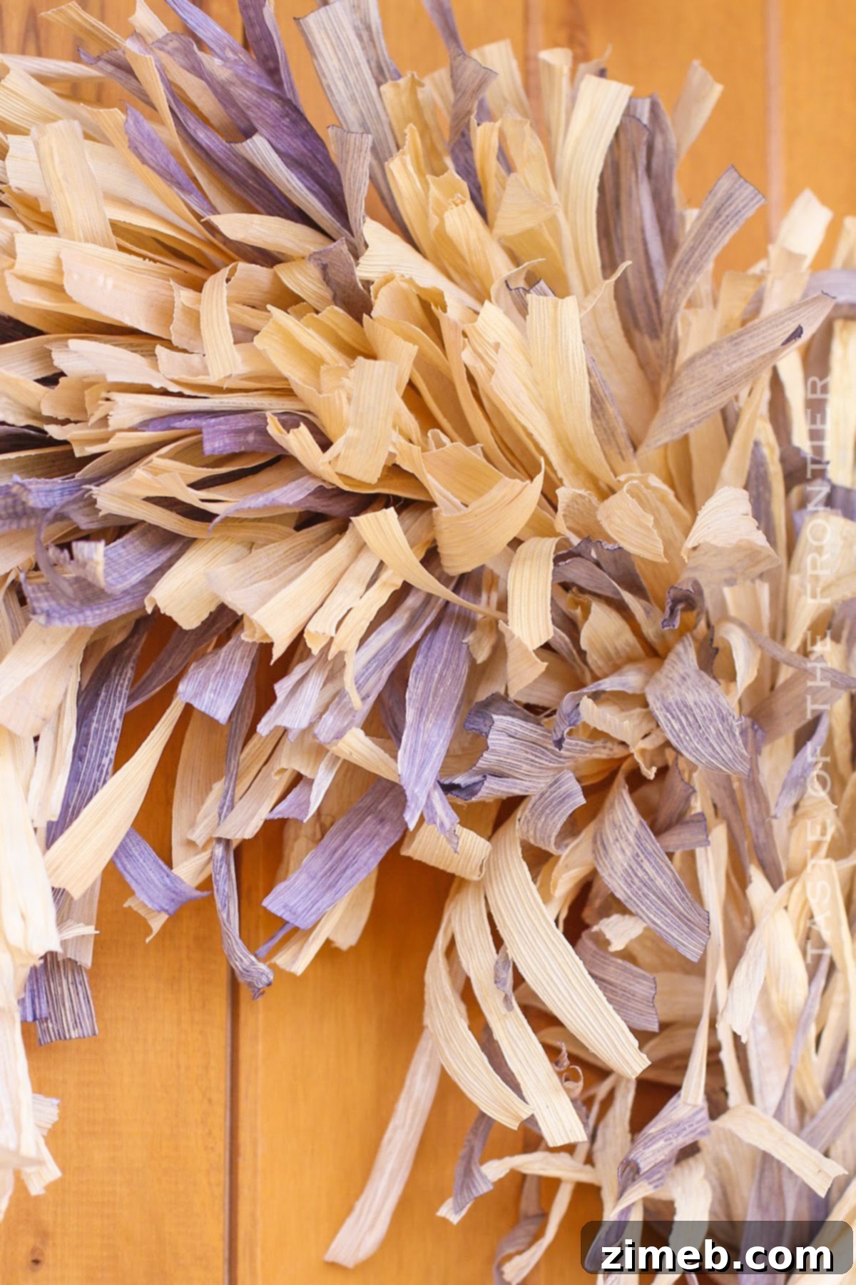 Detail view of a fall wreath with corn husks, featuring natural and dyed textures