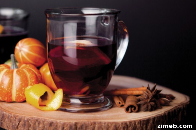 A steaming mug of traditional Vin Chaud, or French Mulled Wine, garnished with fresh orange slices and fragrant cinnamon sticks, radiating warmth and holiday cheer.