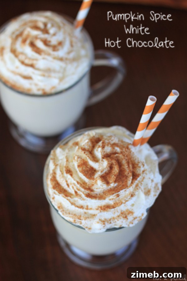 A cozy mug of Pumpkin Spice White Hot Chocolate, topped with a generous swirl of whipped cream and a sprinkle of pumpkin pie spice, offering a sweet and comforting autumn-winter flavor.