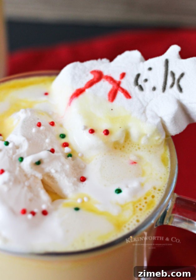 A hand holding a mug of Eggnog Hot Chocolate with festive toppings