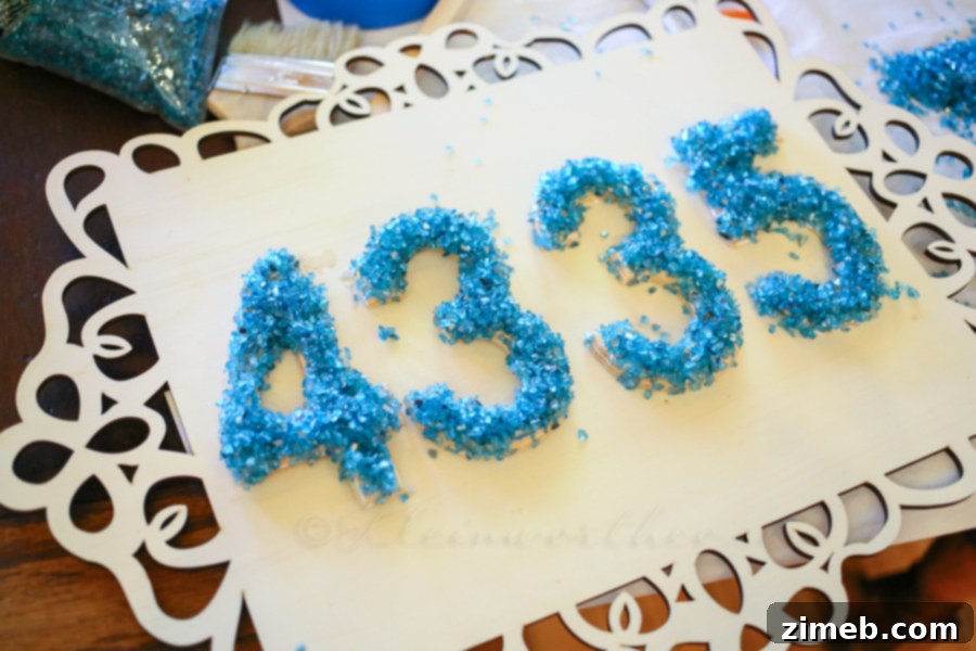 Modern Address Plaque 4 Close-up of a house number being decorated with turquoise glass pieces using Elmer's ProBond Advanced adhesive.