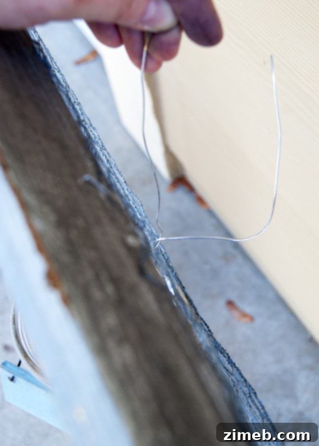 Close-up of a mason jar being securely wired to the chicken wire frame