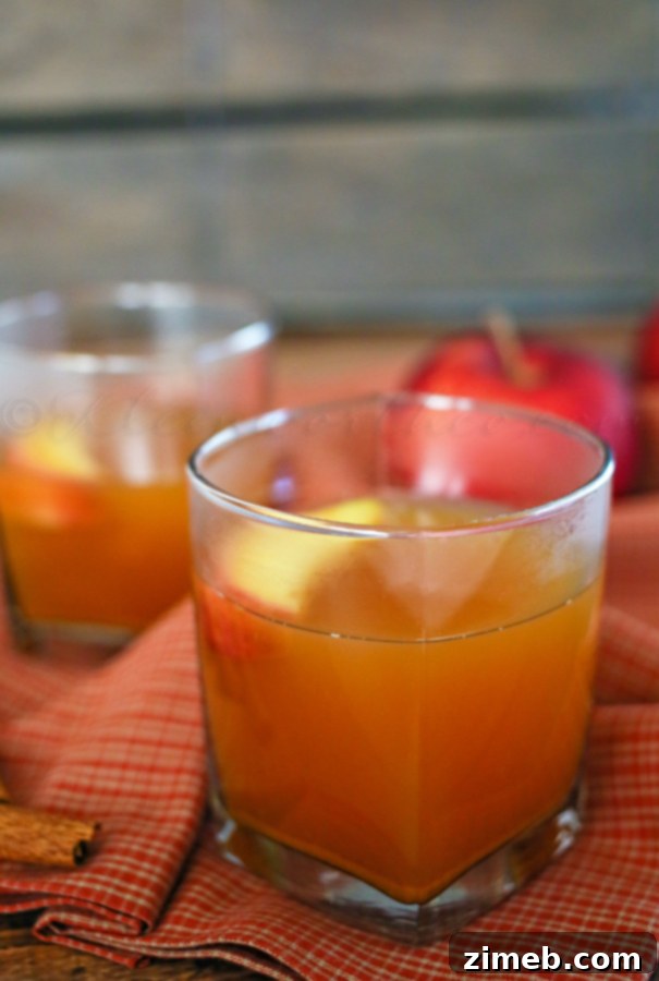 A steaming mug of Honey Bourbon Apple Cider garnished with apple slices and cinnamon sticks, evoking a warm holiday feeling.
