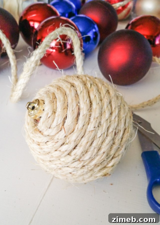 Wildcrafted Wonders 6 Detailed image showing the process of making a sisal-wrapped Christmas ornament, with sisal twine being neatly applied to a spherical ornament base using hot glue