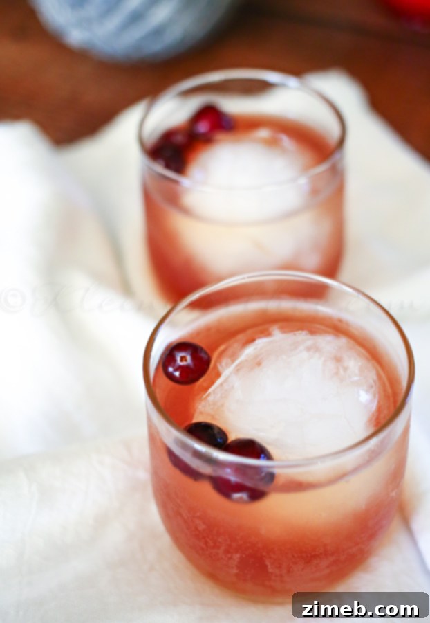 Crimson Ember 2 Cranberry Whiskey Cocktail being poured into a glass, garnished with fresh cranberries.