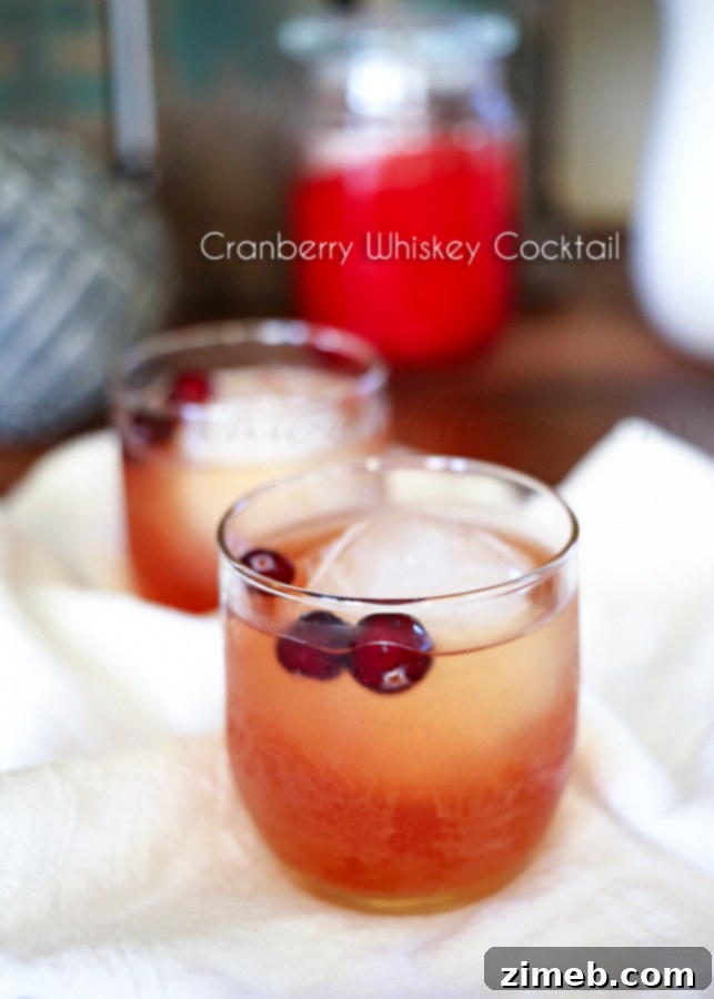 Crimson Ember 4 Cranberry Whiskey Cocktail with a large whiskey ice ball in a rocks glass, ready to be served.