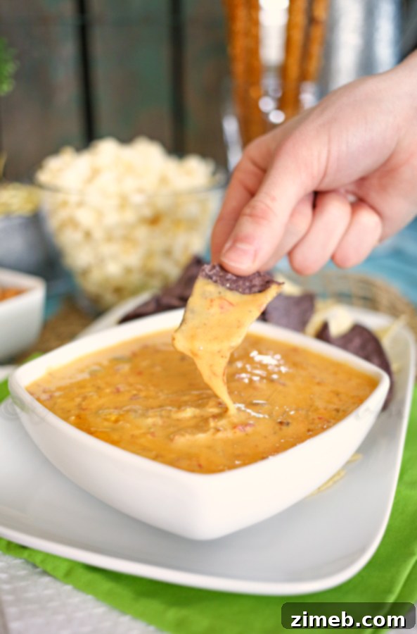 A bowl of Carnitas Queso ready for game day snacking, highlighted by soft lighting.